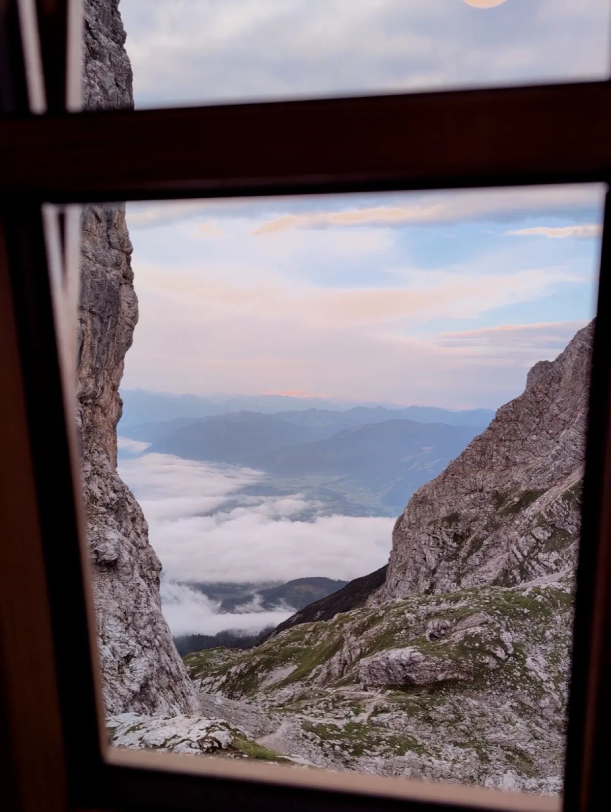 A cloud-filled valley framed by a mountain-hut window photographed with the Steine film look